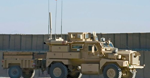 A Cougar MRAP 4×4 patrol vehicle with a trailer and Polish flags at Polish Forward Operating Base Ghazni in Afghanistan in 2008.
