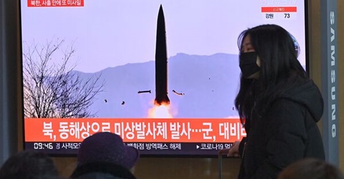 A woman walks past a television screen in Seoul showing a news broadcast with footage of North Korea's most recent missile test, which featured what appeared to be KN-23 short-range ballistic missiles.