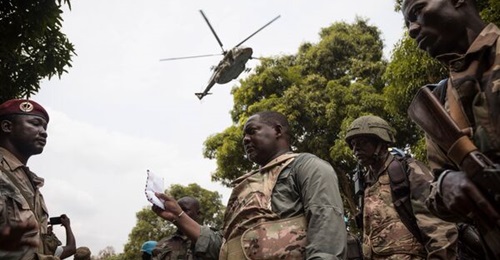 CAR Prime Minister Firmin Ngrébada (centre) talks to troops as a Russian Mi-8AMTSh helicopter flies overhead on the road between Boali and Bangui on 10 January.