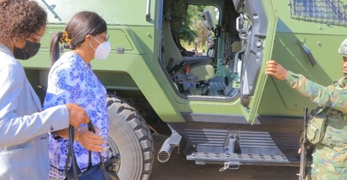 A Rwandan soldier shows a visiting Mozambican delegation an armoured vehicle that can be identified as a Cobra II.