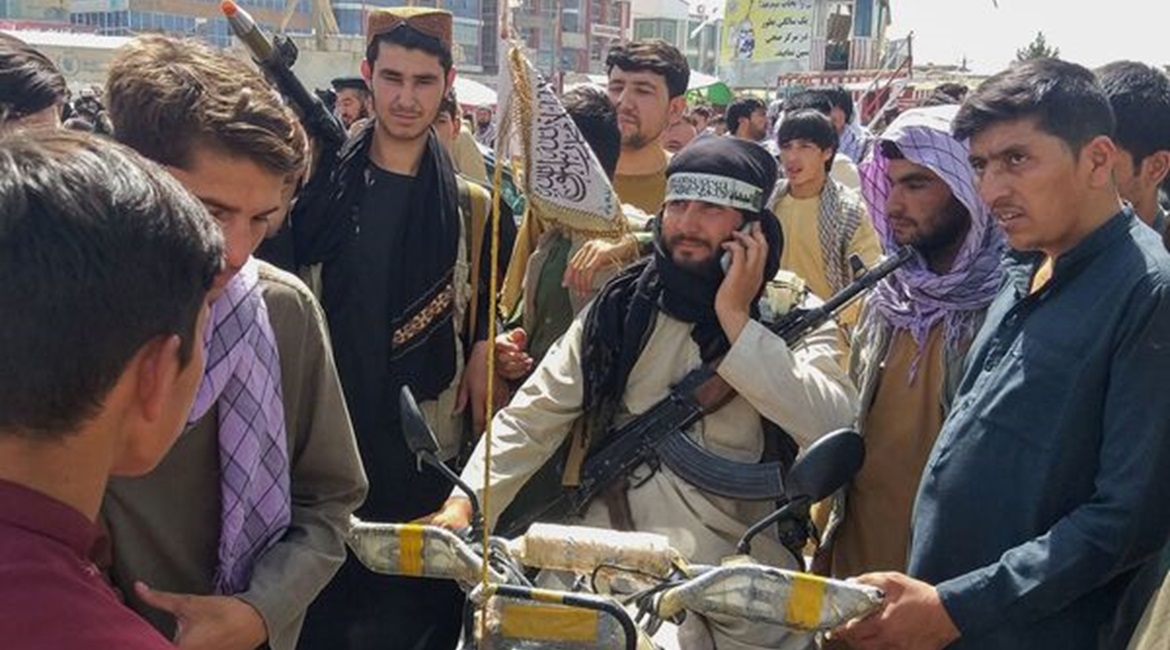 A Taliban fighter (centre) surrounded by locals at Pul-e-Khumri, the capital of Afghanistan's northern Baghlan Province, on 11 August. The city, located about 200 km north of Kabul, is one of ten Afghan provincial centres captured by the Taliban since ...
