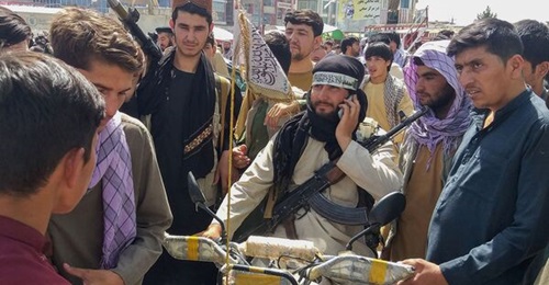 A Taliban fighter (centre) surrounded by locals at Pul-e-Khumri, the capital of Afghanistan's northern Baghlan Province, on 11 August. The city, located about 200 km north of Kabul, is one of ten Afghan provincial centres captured by the Taliban since ...