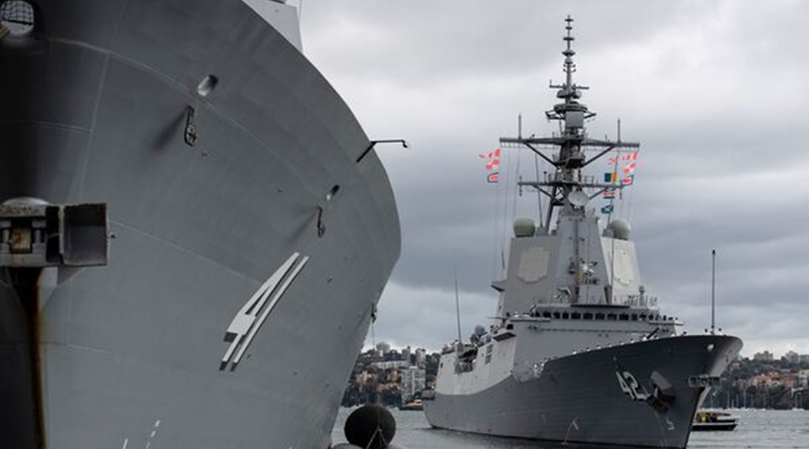 HMAS 
        
         (in the background) departing its home port at Fleet Base East, Sydney, on 11 March to trial its Aegis Weapon System with the US Navy.