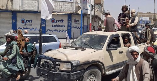 Taliban fighters drive an Afghan National Army vehicle through a street in Kandahar shortly after capturing the southern city on 13 August.