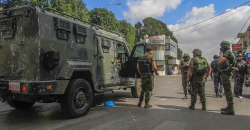 Palestinian National Security Forces personnel stand next to an Al-Jawad during protests in the West Bank city of Nablus on 20 September.