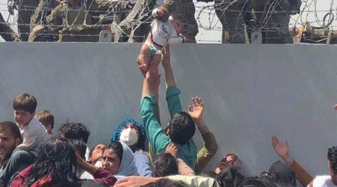 A US Marine grabs an infant over a fence of barbed wire during the evacuation at Hamid Karzai International Airport in Kabul, Afghanistan, on 19 August 2021. Dozens of people were killed a week later on 26 August, at the Abbey Gate at the airport, as t...