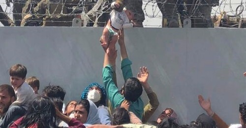 A US Marine grabs an infant over a fence of barbed wire during the evacuation at Hamid Karzai International Airport in Kabul, Afghanistan, on 19 August 2021. Dozens of people were killed a week later on 26 August, at the Abbey Gate at the airport, as t...