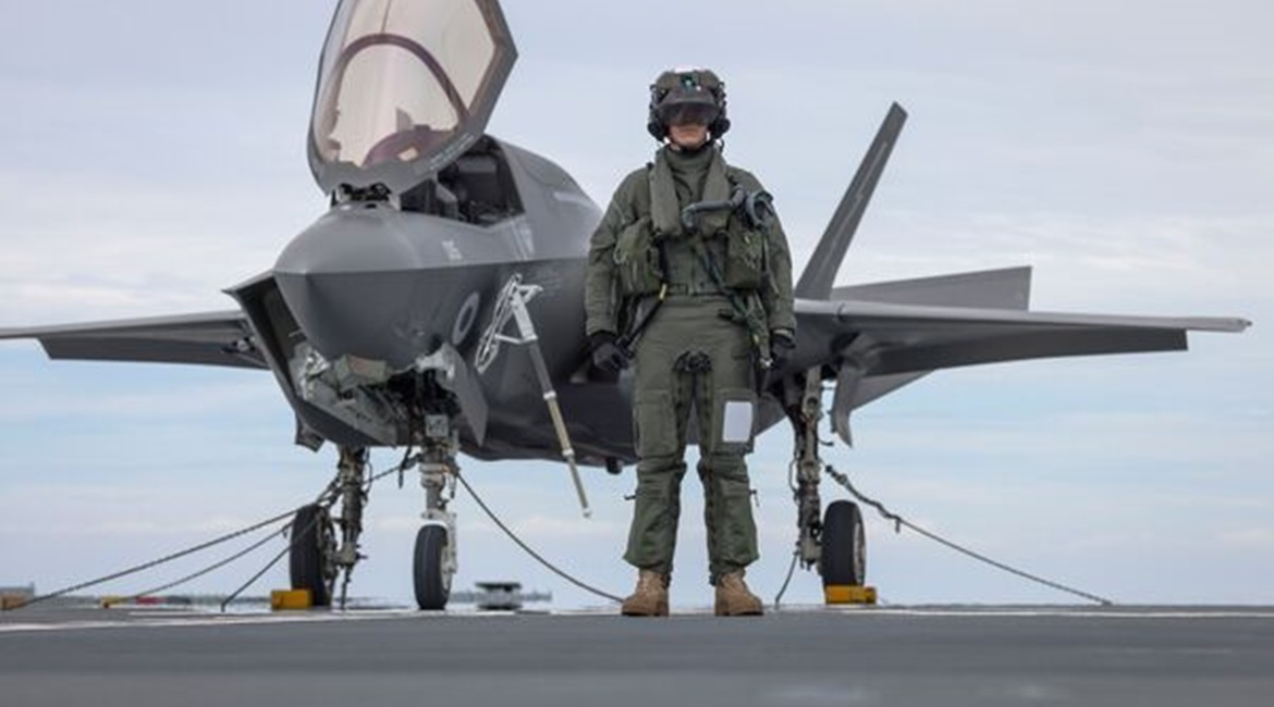 F-35B pilot, Squadron Leader Will, stands in front of his aircraft aboard 
        
        .