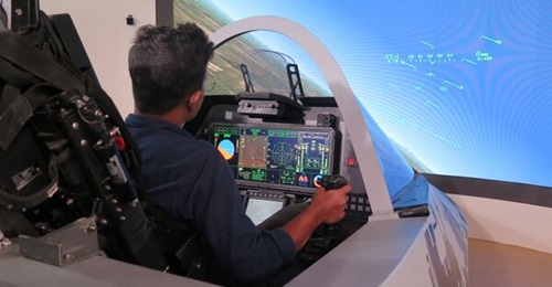 A visitor to the Aero India 2023 show sits in an AMCA cockpit simulator set up by the DRDO.