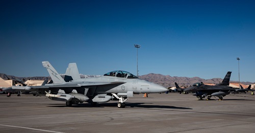 A Royal Australian Air Force EA-18G Growler taxis past a US Air Force F-16 Falcon at Nellis Air Force Base, Nevada, during Exercise 'Red Flag 23-1'. The Growler is equipped with three AN/ALQ-99 pods, including one AN/ALQ-99 (low-band) pod in the centre...