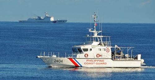 A Philippine Coast Guard boat sails past a China Coast Guard vessel during a 2019 encounter in the South China Sea. The PCG has recently reported the large presence of Chinese militia vessels in waters claimed by Manila.