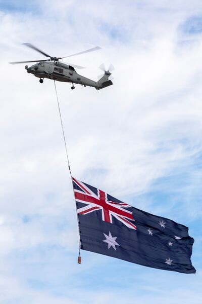 A Royal Australian Navy MH-60R helicopter carries the Australian national flag during the 2023 Avalon International Airshow.