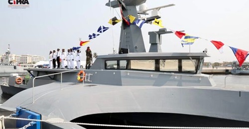 An Ocean Eagle 43 patrol vessel is seen with an unusual weapon during the inauguration of Angola's Soyo Naval Base. A 12-tube launcher mounted on the deck behind the bridge is obscured by the sailors standing in front of it.