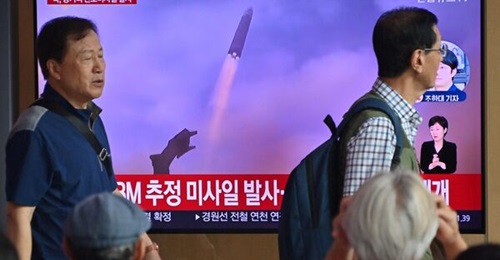 People watch a television screen showing a news broadcast with file footage of a North Korean missile test, at a railway station in Seoul on 12 July. North Korea fired a Hwasong-18 ICBM earlier that day.