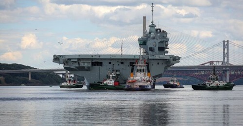 The Royal Navy's aircraft carrier HMS 
        
         departs the harbour area of Rosyth dockyard on 22 July 2023 following nine months of repairs.
