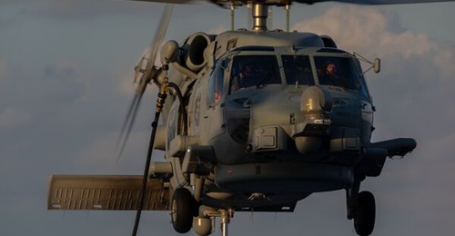 A Royal Australian Navy MH-60R helicopter conducts an in-flight refuel while embarked on HMAS 
        
        .