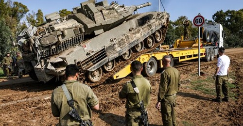 An Israeli battle tank rolls onto a trailer truck at a position along the border with the Gaza Strip and southern Israel on 2 January 2024, amid the ongoing conflict between Israel and the militant group Hamas (Photo by JACK GUEZ/AFP via Getty Images).