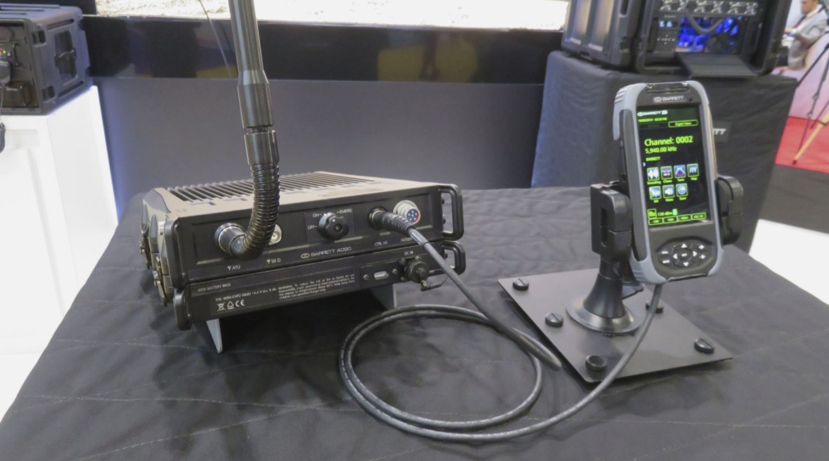 The Barrett PRC-4090 as shown at DSEI 2019 in the manpack configuration. The transceiver is mounted above the battery pack, with the control handset to the right.