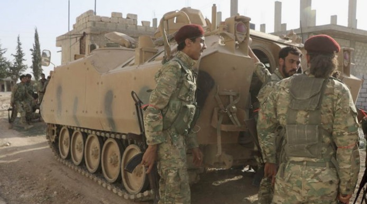 Turkish-backed Syrian fighters are seen with an ACV-15 APC in the Syrian border town of Tal Abyad on 10 October 2019.