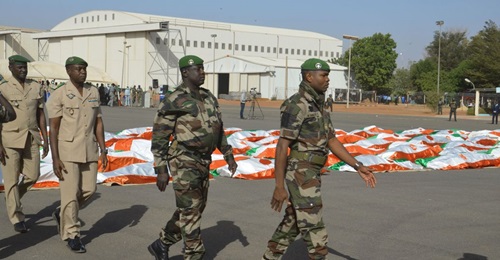 Nigerien military personnel walk past the corpses of soldiers killed in a 10 December 2019 attack on a military base in western Niger.