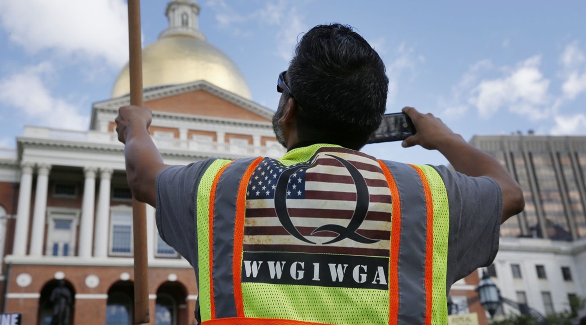 A demonstrator wearing a QAnon vest attends a 'No Mandatory Flu Shot' rally outside the State House in Boston, Massachusetts, on 30 August 2020. The acronym on his bib, WWG1WGA, is a common QAnon rallying cry, meaning 'Where We Go One, We Go All'.