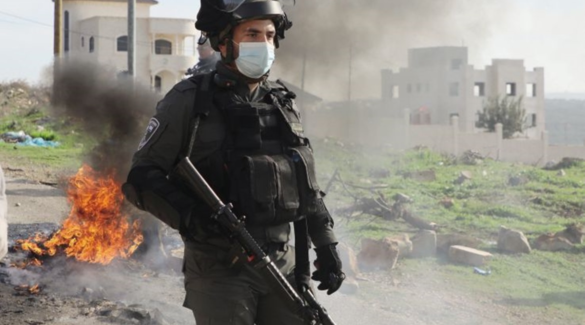 An Israeli security guard stands by burning tyres amid clashes with Palestinian protesters following their demonstration against the expansion of settlements in the town of Salfit, in the Israeli-occupied West Bank, on 4 December 2020. Public unrest in...