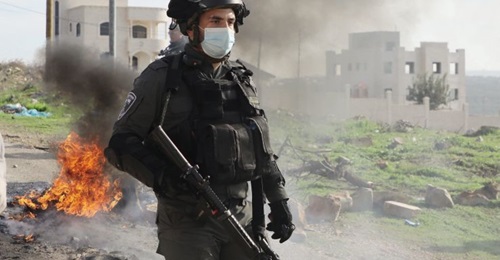An Israeli security guard stands by burning tyres amid clashes with Palestinian protesters following their demonstration against the expansion of settlements in the town of Salfit, in the Israeli-occupied West Bank, on 4 December 2020. Public unrest in...