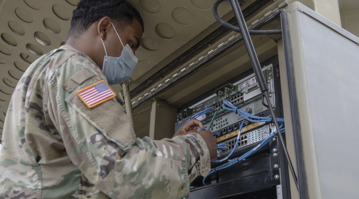 A US Army specialist with the 1st Armored Division Combat Aviation Brigade uses a Category 5 cable to establish a network connection at Camp Atterbury Joint Maneuver Training Center in Indiana.