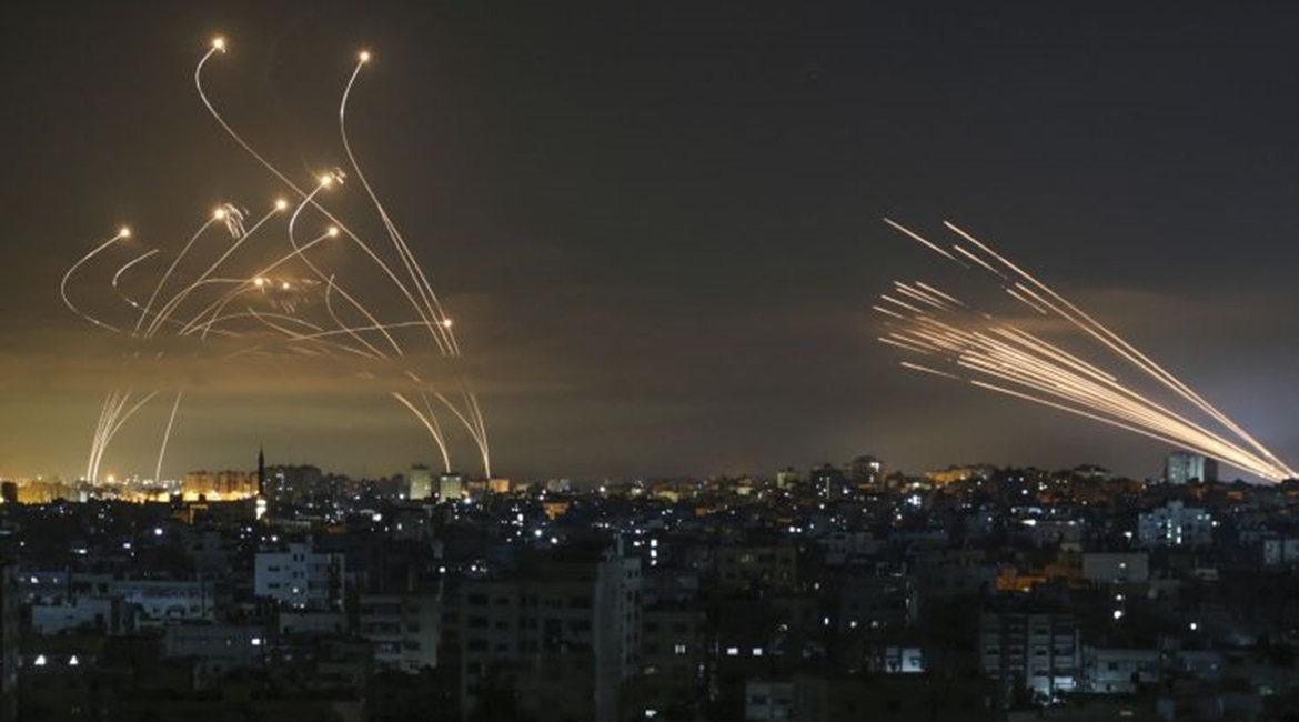 Iron Dome launchers in southern Israeli fire Tamir interceptors (left) against a barrage of rockets coming from the Gaza Strip, the contrails of which can be seen (right) on the night of 14 May.