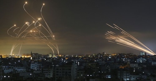 Iron Dome launchers in southern Israeli fire Tamir interceptors (left) against a barrage of rockets coming from the Gaza Strip, the contrails of which can be seen (right) on the night of 14 May.